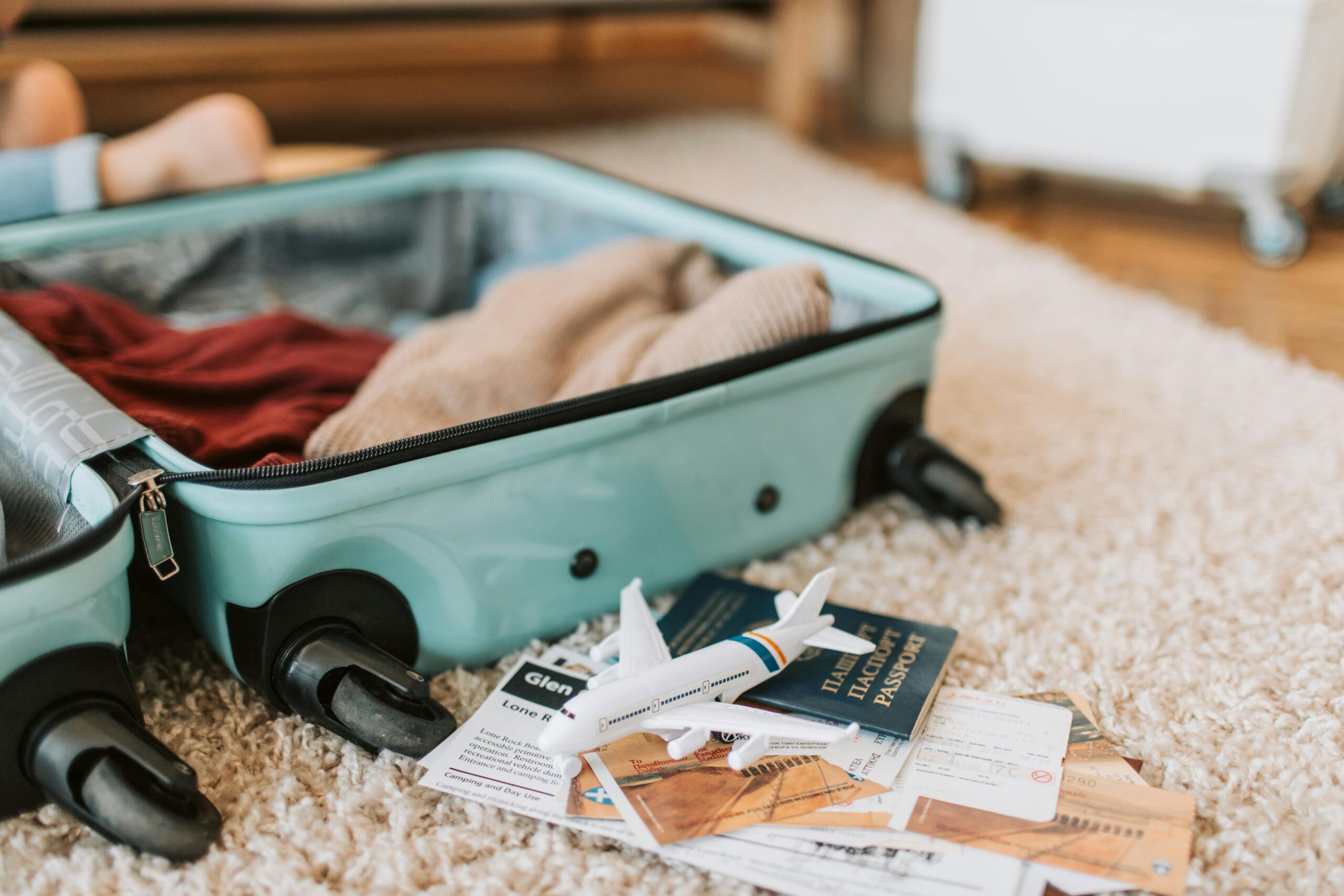 Open suitcase with travel essentials like passport, tickets, and clothes – perfect for Saudi Arabia Umrah, Hajj, and tourism travel packing 2025.