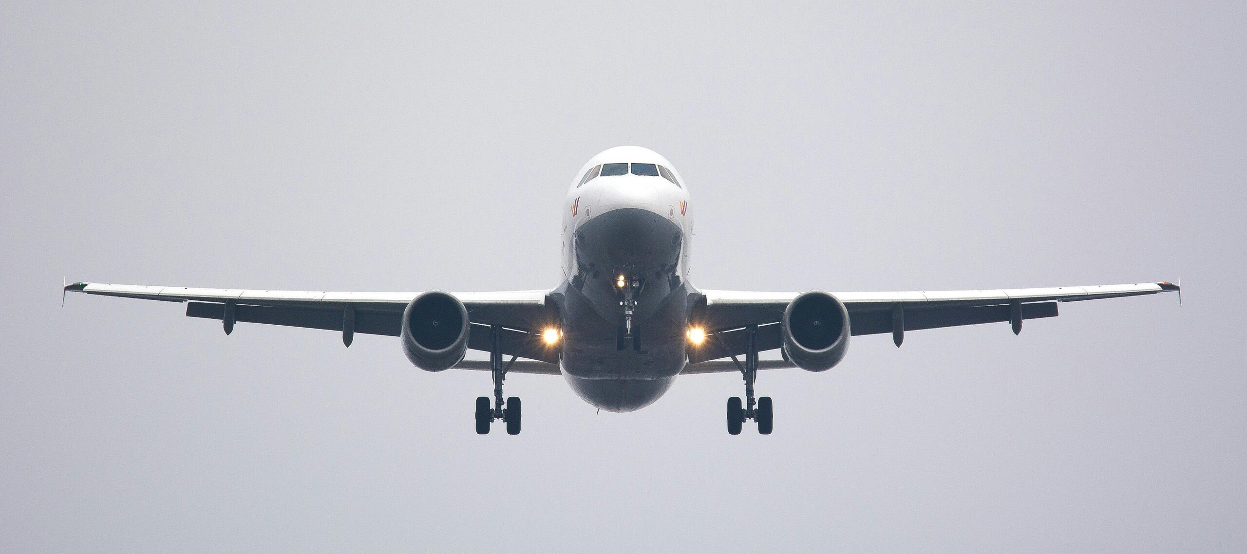 A commercial airliner captured head-on, preparing to land against a cloudy sky. mashaer fleet